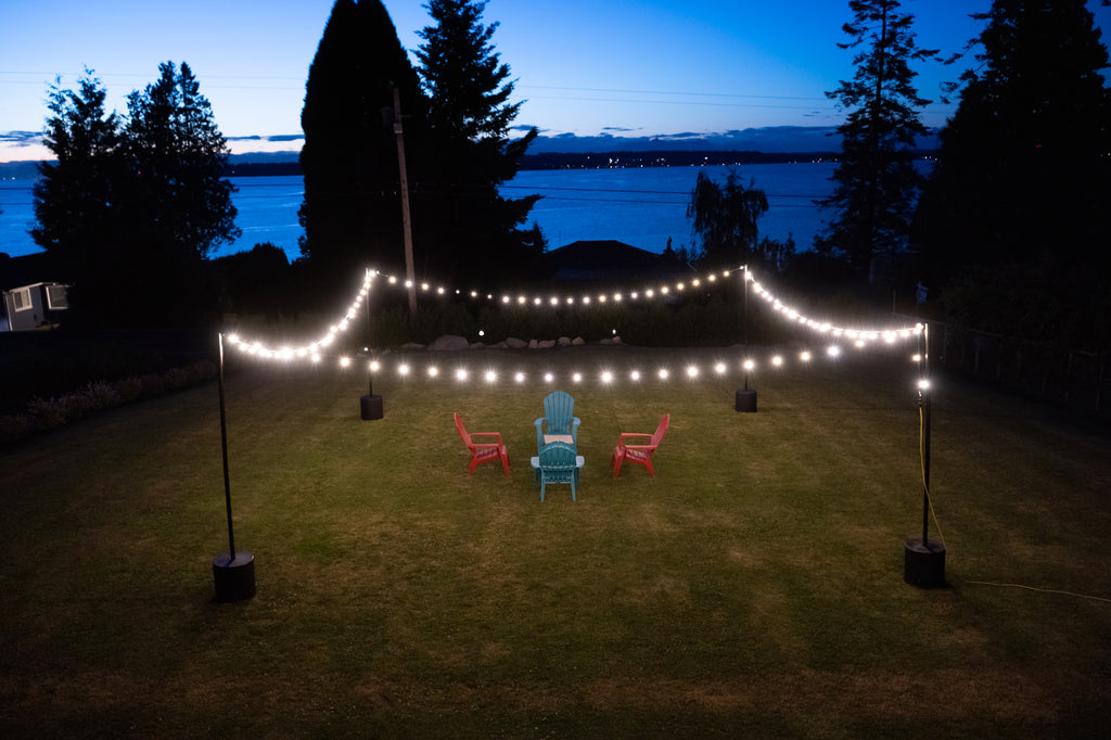 Portable string light pole stands with string lights in backyard