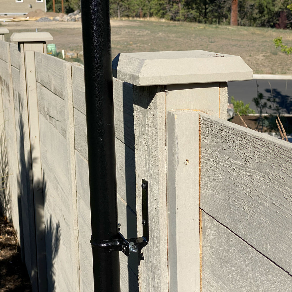 String light pole attached to fence with bracket